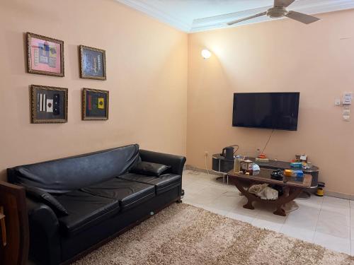 a living room with a black leather couch and a television at Fitini appart in Bamako