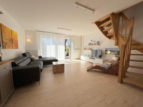 a living room with a couch and a staircase at Haus Strandgut in Hooksiel in Wangerland