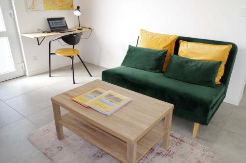 a living room with a green couch and a coffee table at Les Blés d'Or - Parking privé, Terrasse, Clim, Netflix, Au Calme in Hem-Lenglet