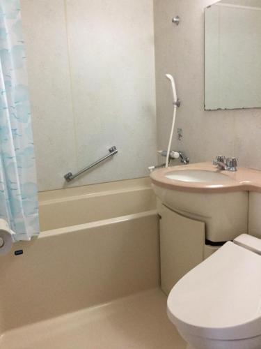 a bathroom with a toilet and a sink and a tub at Utsunomiya Inter Resort Hotel & Golf Tsuru Country Club in Utsunomiya