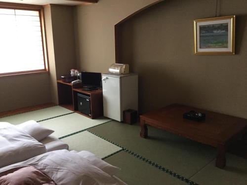 a room with a bed and a table and a refrigerator at Utsunomiya Inter Resort Hotel & Golf Tsuru Country Club in Utsunomiya