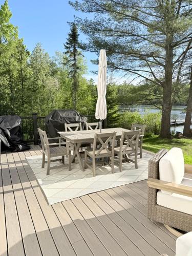 a wooden deck with a table and chairs and an umbrella at Driftwood on Torch River in Rapid City