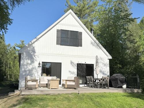a white barn with chairs and tables on a deck at Driftwood on Torch River in Rapid City