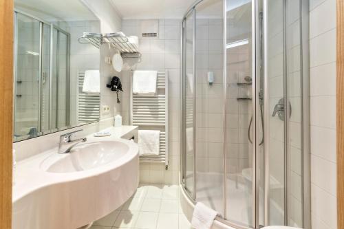 un bagno con lavandino e doccia di Hotel Post - OlangCard included a Valdaora