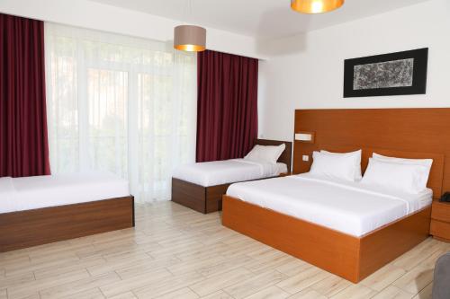 a hotel room with two beds and red curtains at Prince Adriatic Resort in Shëngjin
