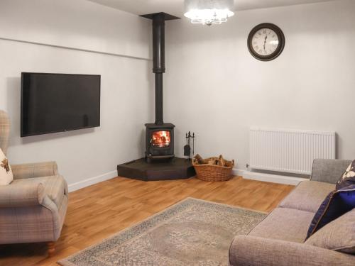 a living room with a fireplace and a flat screen tv at Stable End in Llandysul