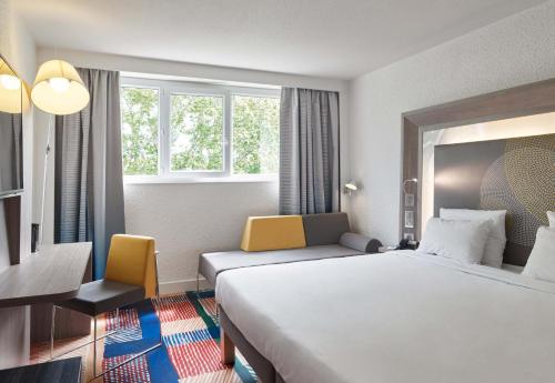 a hotel room with a bed and a desk and window at B&B HOTEL Cergy Port 4 étoiles in Cergy