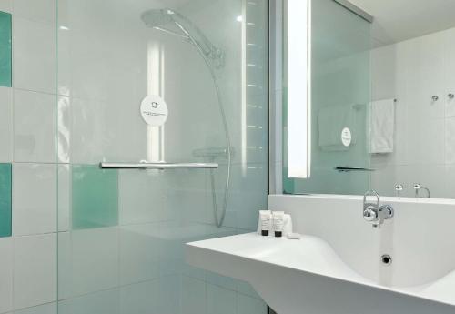 a white bathroom with a sink and a shower at B&B HOTEL Cergy Port 4 étoiles in Cergy