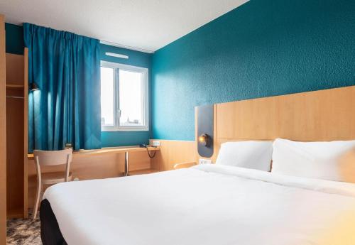 a bedroom with a large bed and a blue wall at B&B HOTEL Amiens Centre Cathédrale in Amiens