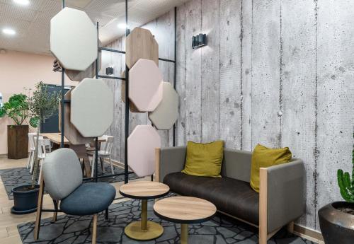 a living room with a couch and two tables and chairs at B&B HOTEL Lille Villeneuve d'Ascq Grand Stade 3 étoiles in Villeneuve d'Ascq