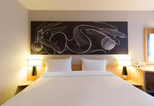 a bedroom with a large white bed with two lamps at B&B HOTEL Reims Centre Erlon in Reims
