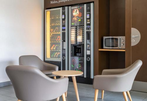 two chairs and a table in front of a vending machine at B&B HOTEL Lyon Eurexpo Chassieu in Chassieu