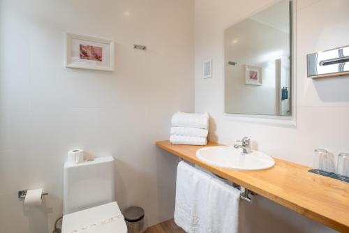 a bathroom with a sink and a toilet and a mirror at Hotel Silken Don Pepe y Don Pepe Ría in Ribadesella