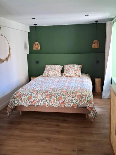 a bedroom with a bed with a green headboard at Les 3 suites in Issoire