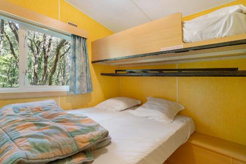 a small bedroom with a bed and a window at 23.Mobil-home option clim-5pers in Calviac