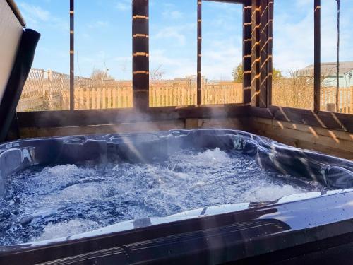 a jacuzzi tub with water in it at Algwen Cabin in West Walton