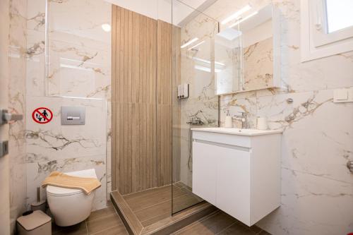a white bathroom with a toilet and a sink at Green Almond's Comfort Apartment in Orfánion