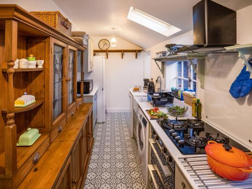 a kitchen with wooden cabinets and a stove top oven at Flint Cottage in Saxmundham