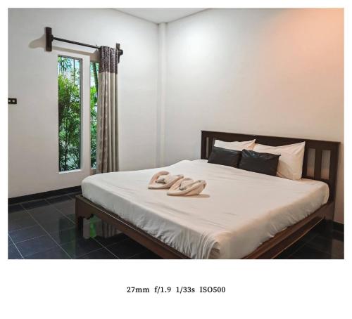 ein Schlafzimmer mit einem Bett, auf dem zwei Hausschuhe liegen in der Unterkunft king s hotel in Mae Sot