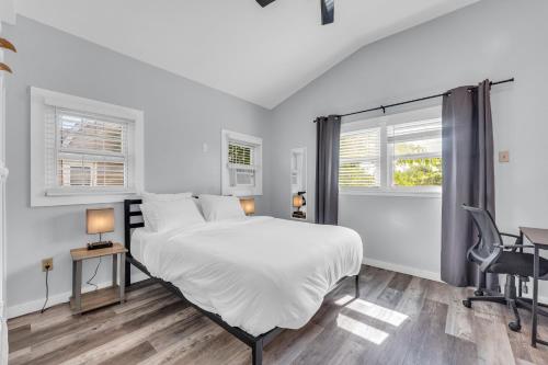 a white bedroom with a bed and two windows at Stay with Jay - Quarta Suite in Cleveland