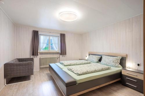 a bedroom with a bed with a chair and a window at Ferienwohnung Schaule in Bolsterlang