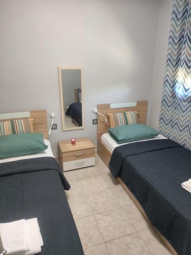 a bedroom with two beds and a mirror at Arethousa House in Nea Vrasna