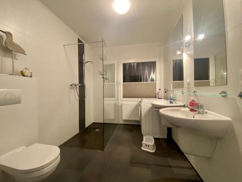 a white bathroom with a toilet and a sink at Haus Rosenwind in Wangerland