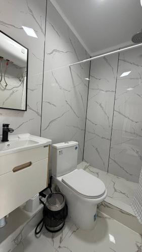 a white bathroom with a toilet and a sink at Comfort Point Hotel in Bishkek