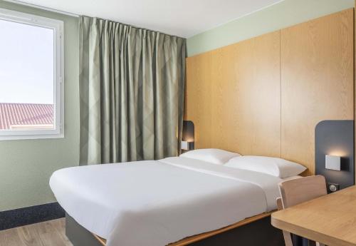 a large white bed in a room with a window at B&B HOTEL Martigues Port-de-Bouc in Port-de-Bouc