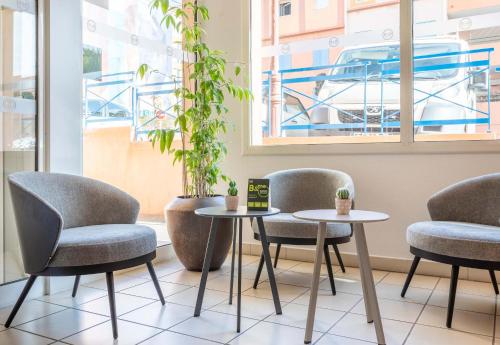 a room with two tables and chairs and a window at B&B HOTEL Martigues Port-de-Bouc in Port-de-Bouc