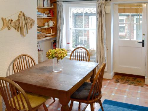 a dining room table with chairs and a vase of flowers at Sea Breeze in Blakeney
