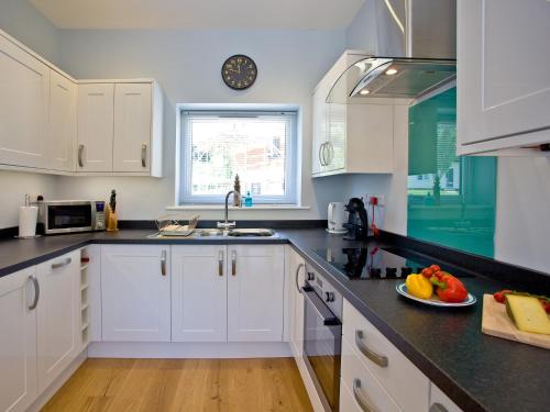 a kitchen with white cabinets and a plate of fruit on the counter at Dunlin 4 - The Cove in Brixham