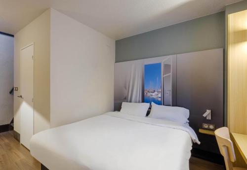 a bedroom with a large white bed and a chair at B&B HOTEL FREJUS Puget-sur-Argens in Fréjus