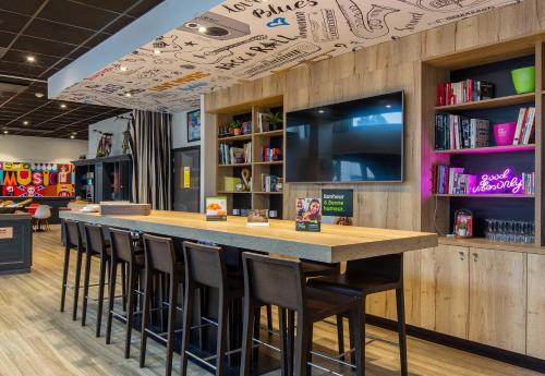a bar in a library with chairs and a tv at B&B HOTEL Orléans Centre Foch in Orléans