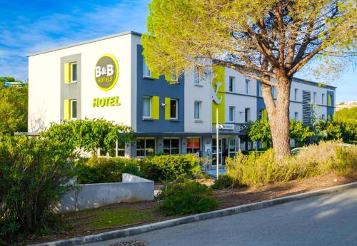 an office building with a tree in front of a street at B&B HOTEL Antibes Sophia Antipolis in Biot
