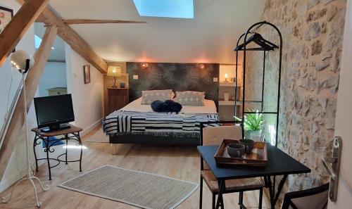 a bedroom with a bed and a desk and a tv at Les chambres de Mona in Tauriac