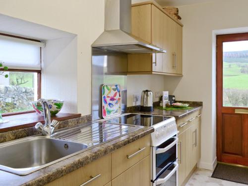 a kitchen with a sink and a stove top oven at Beuchan Cottage Keir Mill in Closeburn