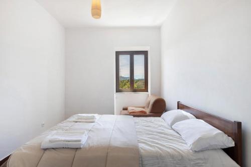 a white bedroom with a large bed and a chair at Le Vallocchie in Concerviano