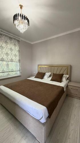 a bedroom with a large bed and a chandelier at Comfort Point Hotel in Bishkek
