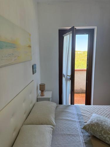 a bedroom with a bed and a door to a patio at La Vela Apartment in Stintino