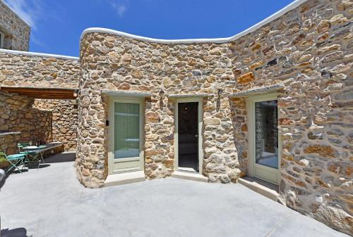 a stone building with two doors and a patio at Koumaros Cycladic Suites in Koumáros