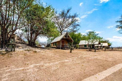 a house with a thatched roof on a dirt field at Chobe River Campsite in Ngoma