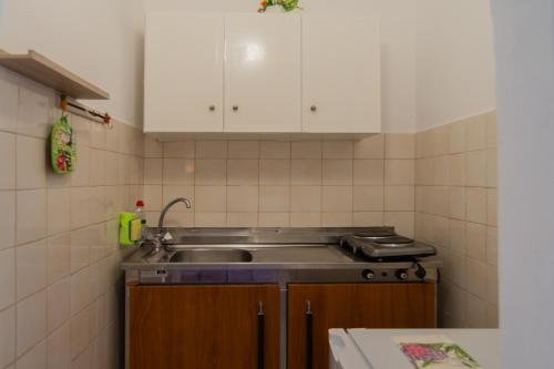 a small kitchen with a sink and white cabinets at Lisipio Studios by Eleni in Paleokastritsa