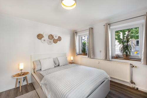 a white bedroom with a bed and two windows at Fewo in der Altstadt - Metter in Bietigheim-Bissingen