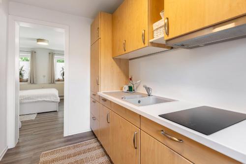 a kitchen with wooden cabinets and a sink and a bedroom at Fewo in der Altstadt - Metter in Bietigheim-Bissingen