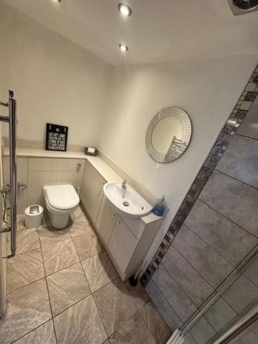 a bathroom with a toilet and a sink and a mirror at Studio sleeps 2 with Parking in Derby