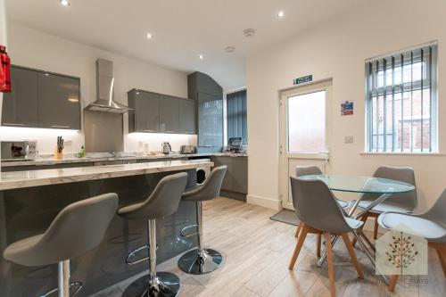 a kitchen with a glass table and some chairs at Fairhurst House in Leigh