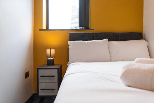 a bedroom with a bed and a lamp on a night stand at Urmston House in Leigh