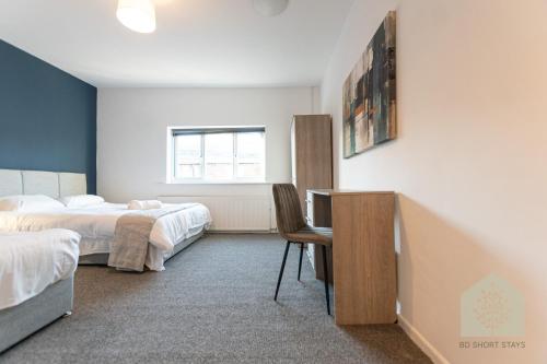 a bedroom with two beds and a desk with a chair at Holt House in Hindley
