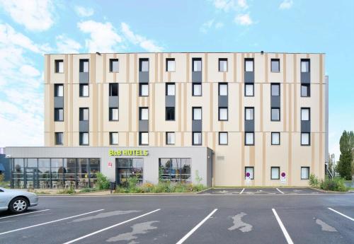 a building with a parking lot in front of it at B&B HOTEL Dreux Nord in Dreux